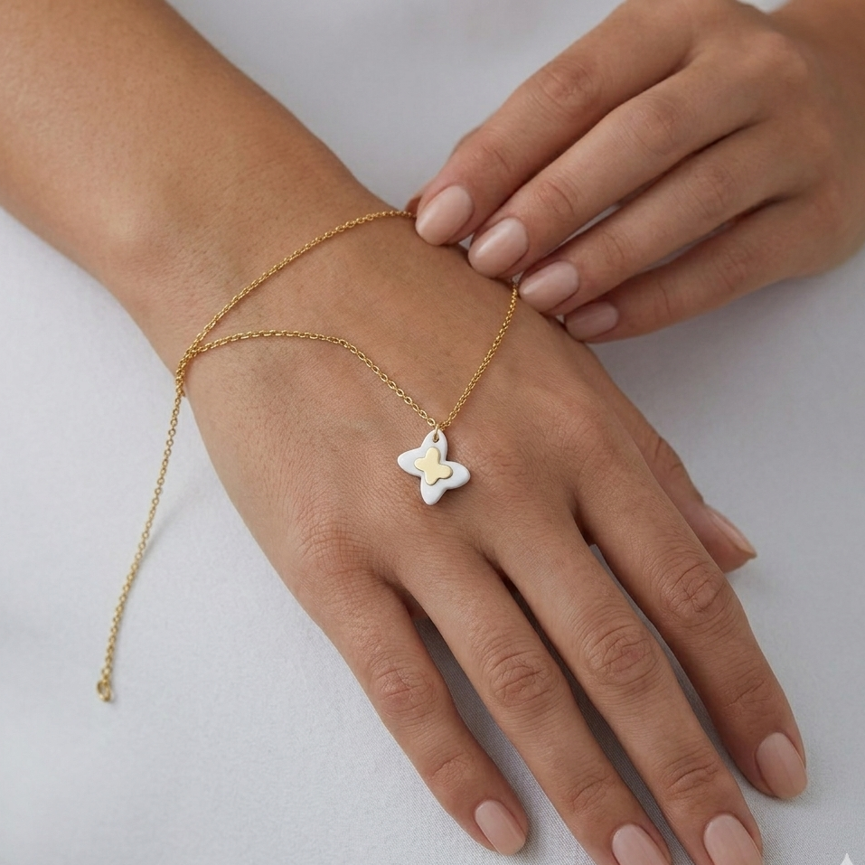 Gold bracelet with a star-shaped pendant on a hand against a white background