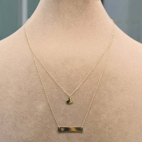 Gold necklace with a heart pendant on a mannequin, displayed against a neutral background.