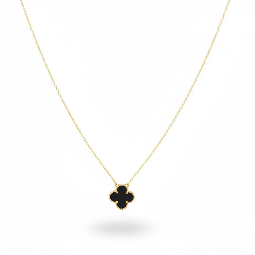 Necklace with a clover-shaped pendant on a beige jewelry display.