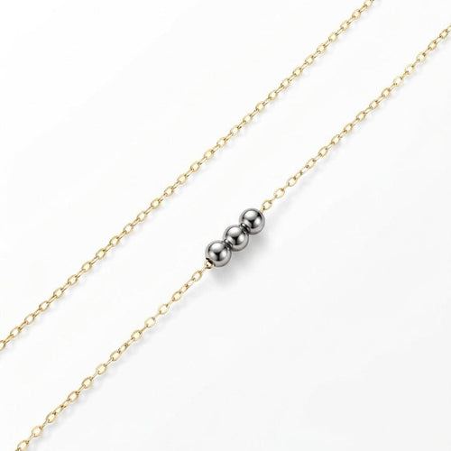 Gold chain necklace with a silver bead on a white background